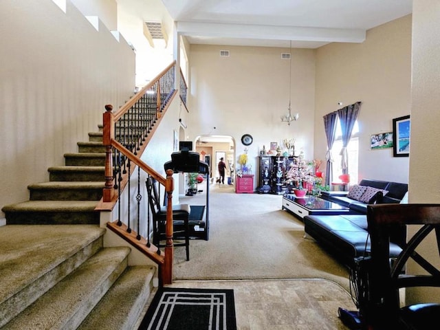 living room with carpet flooring, beam ceiling, a towering ceiling, and an inviting chandelier