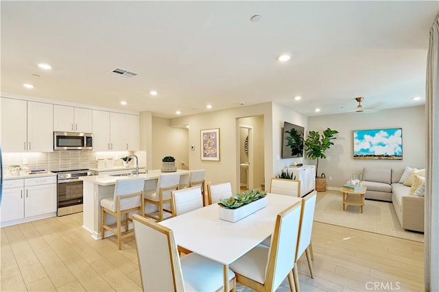 dining room with ceiling fan, sink, and light hardwood / wood-style flooring