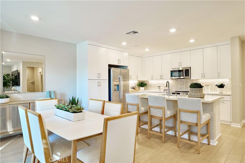 kitchen with a breakfast bar, light wood-type flooring, appliances with stainless steel finishes, and white cabinetry