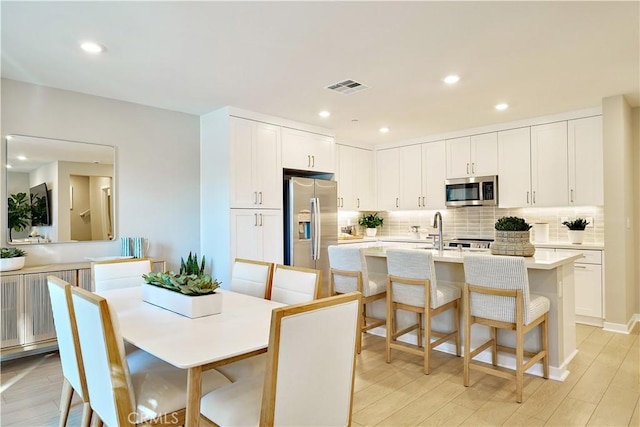 kitchen with a breakfast bar, light wood-type flooring, appliances with stainless steel finishes, and white cabinetry