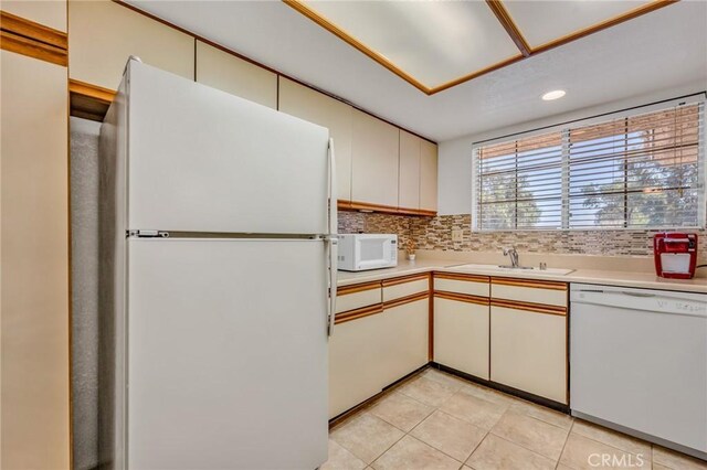 kitchen featuring decorative backsplash, sink, white cabinets, and white appliances