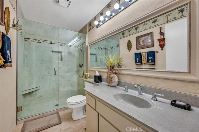 bathroom featuring toilet, vanity, tile patterned floors, and a shower with shower door