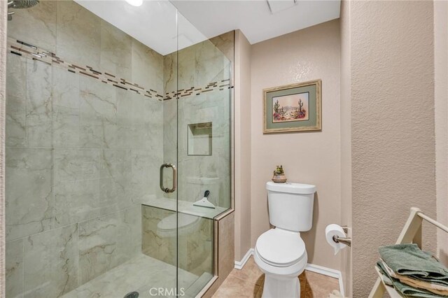 bathroom with toilet, tile patterned floors, and a shower with door