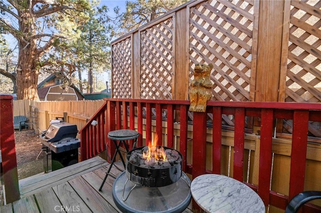 wooden deck featuring grilling area and a fire pit