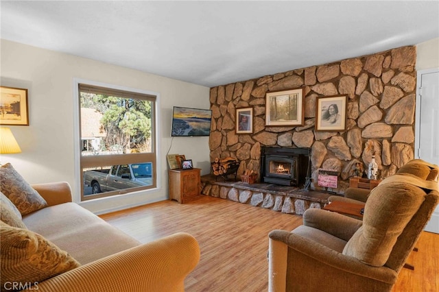 living room featuring a stone fireplace and light hardwood / wood-style floors