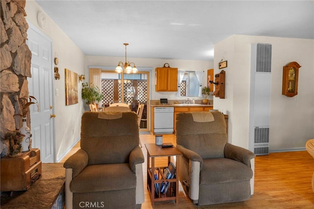 living room featuring light wood-type flooring, a notable chandelier, and sink