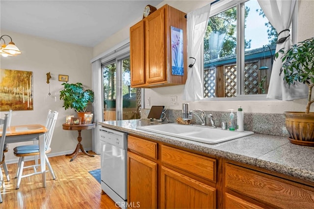 kitchen with white dishwasher, sink, and light wood-type flooring