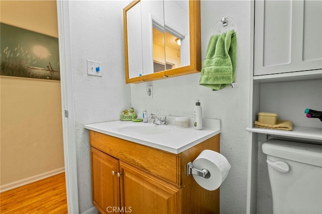 bathroom with toilet, hardwood / wood-style floors, and vanity