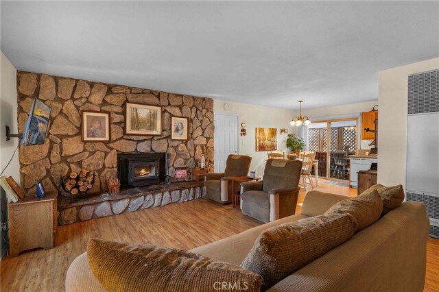 living room with a fireplace, light hardwood / wood-style flooring, and an inviting chandelier