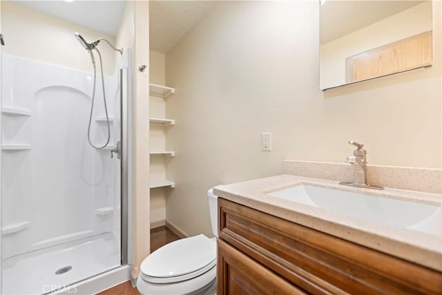 bathroom featuring a shower with shower door, toilet, and vanity