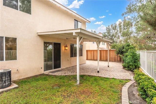 rear view of property with central air condition unit, a lawn, and a patio