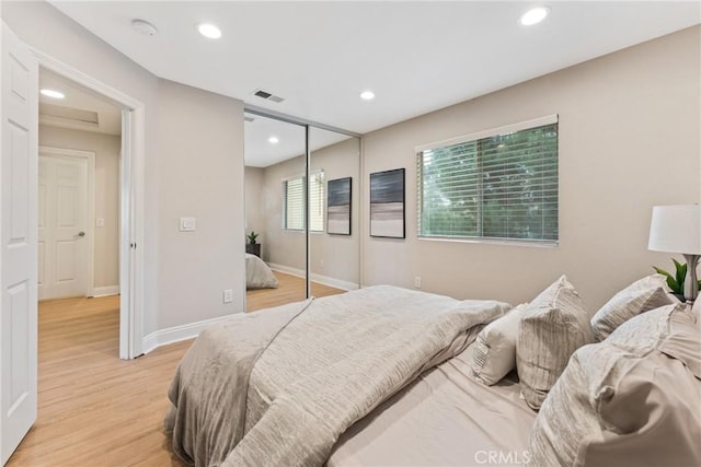 bedroom with light hardwood / wood-style floors and a closet