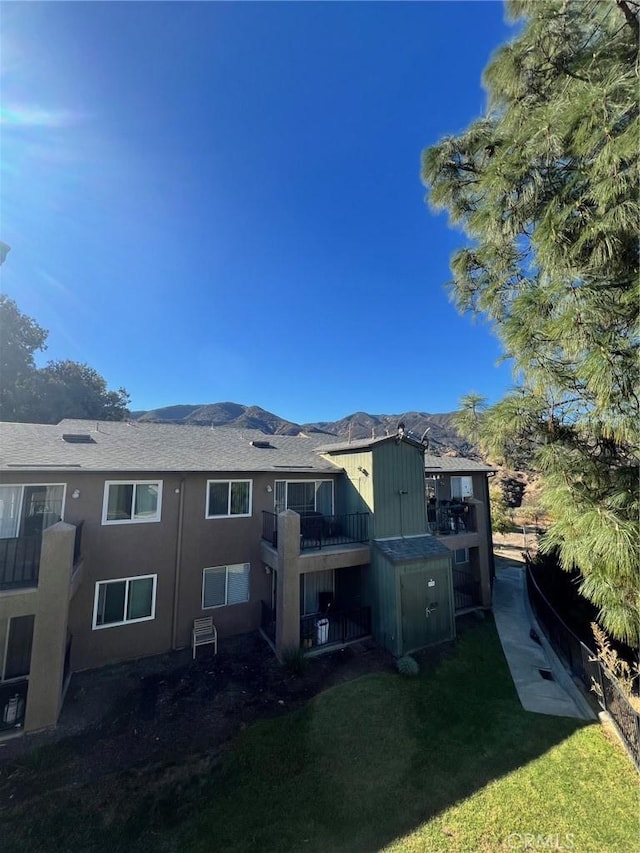 rear view of house with a mountain view and a lawn