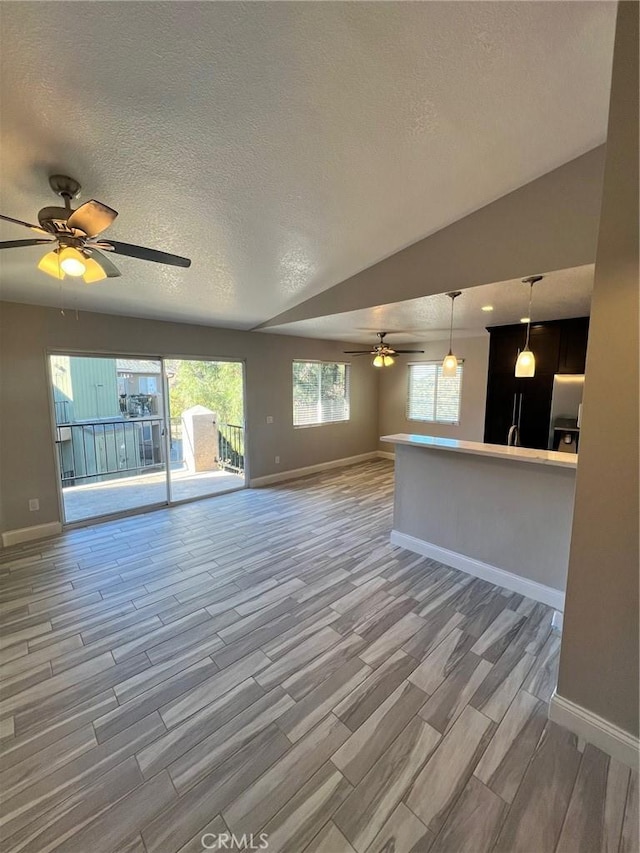 unfurnished living room featuring ceiling fan, lofted ceiling, and a textured ceiling