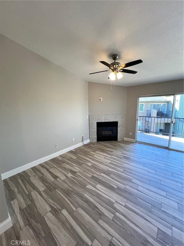 unfurnished living room with a tile fireplace, a textured ceiling, ceiling fan, and light hardwood / wood-style floors