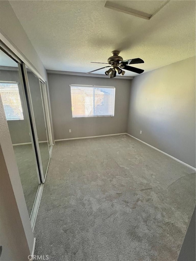 unfurnished bedroom featuring ceiling fan, a closet, a textured ceiling, and carpet