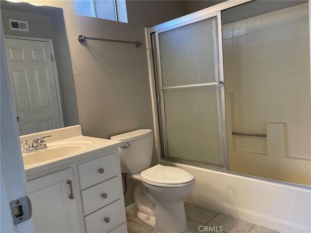 full bathroom featuring vanity, bath / shower combo with glass door, tile patterned floors, and toilet