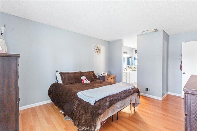 bedroom featuring ensuite bathroom and light hardwood / wood-style flooring