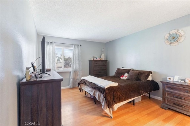 bedroom with a textured ceiling and light hardwood / wood-style flooring