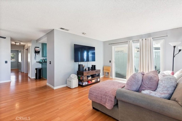 living room with a textured ceiling and light hardwood / wood-style floors