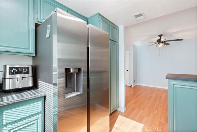 kitchen featuring stainless steel refrigerator with ice dispenser, ceiling fan, blue cabinetry, and light wood-type flooring