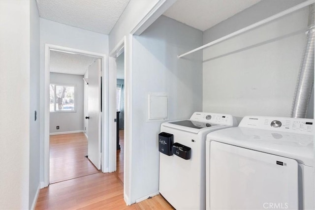 laundry area with a textured ceiling, light hardwood / wood-style floors, and independent washer and dryer