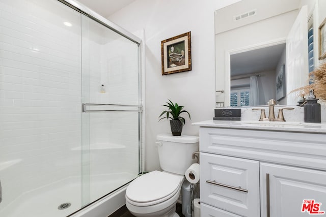 bathroom with toilet, a shower with shower door, and vanity