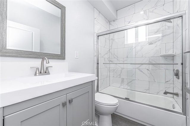 full bathroom featuring combined bath / shower with glass door, vanity, and toilet