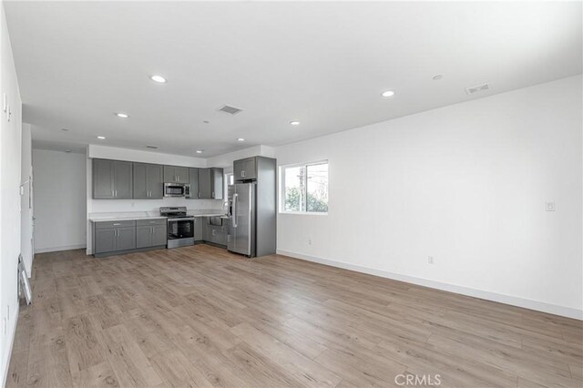 kitchen featuring stainless steel appliances, gray cabinetry, and light hardwood / wood-style flooring