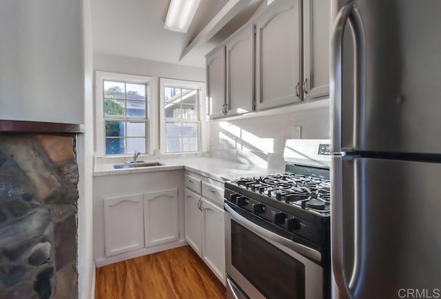 kitchen featuring sink, white cabinetry, appliances with stainless steel finishes, and light hardwood / wood-style flooring