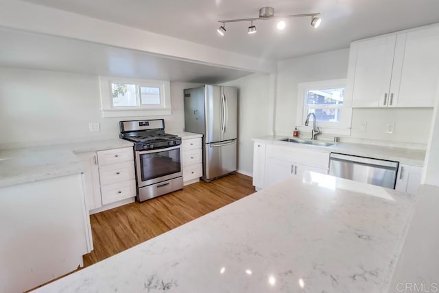 kitchen with light hardwood / wood-style flooring, appliances with stainless steel finishes, sink, white cabinets, and a wealth of natural light