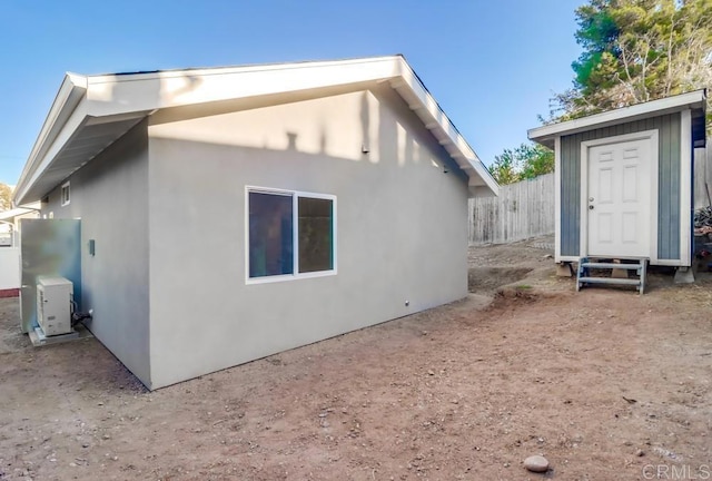 rear view of property with ac unit and a storage shed