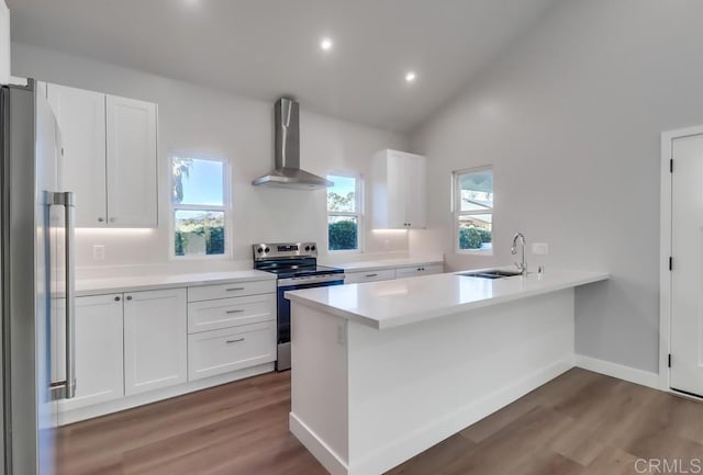 kitchen featuring kitchen peninsula, wall chimney exhaust hood, sink, white cabinetry, and stainless steel appliances