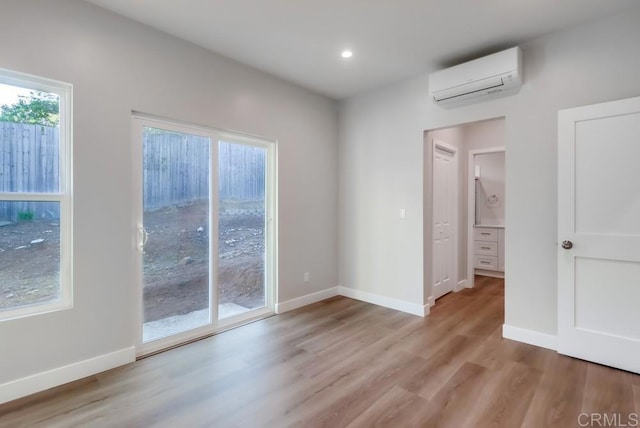 spare room with light hardwood / wood-style floors and a wall unit AC