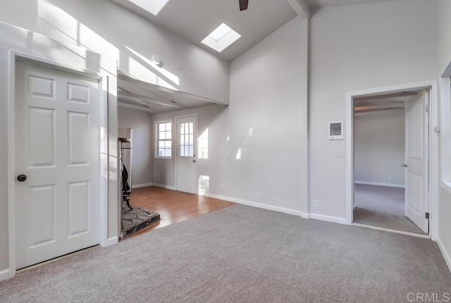 unfurnished living room featuring a skylight, carpet, beamed ceiling, and high vaulted ceiling