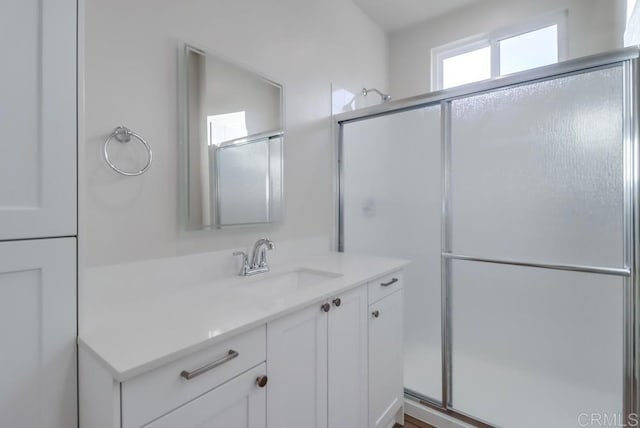 bathroom featuring a shower with shower door and vanity