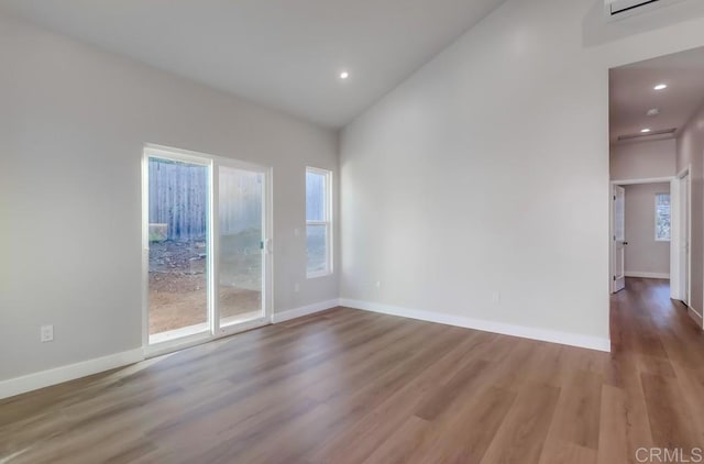 spare room with hardwood / wood-style flooring and lofted ceiling