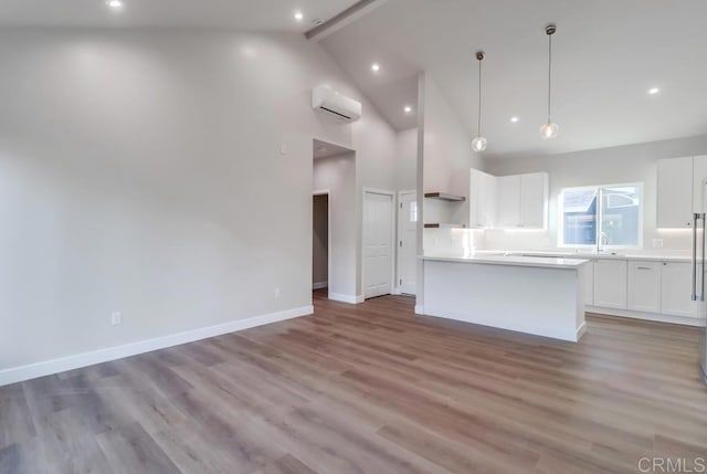 kitchen featuring a center island, decorative light fixtures, white cabinetry, a wall unit AC, and light wood-type flooring