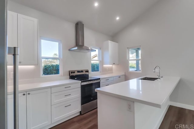 kitchen featuring wall chimney exhaust hood, stainless steel range with electric cooktop, white cabinetry, sink, and kitchen peninsula