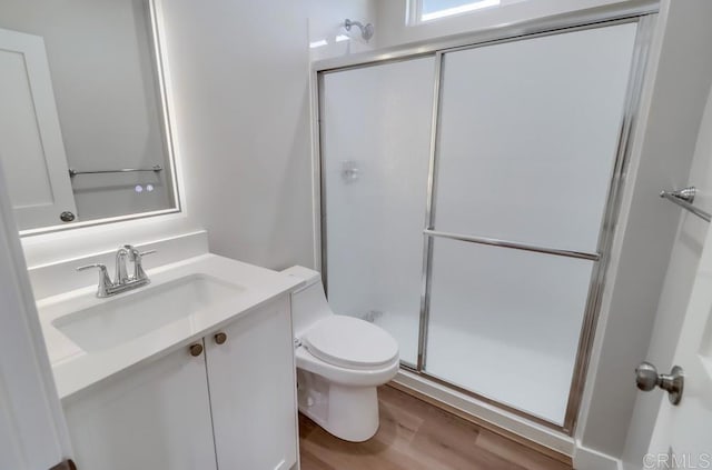 bathroom featuring hardwood / wood-style floors, toilet, a shower with door, and vanity