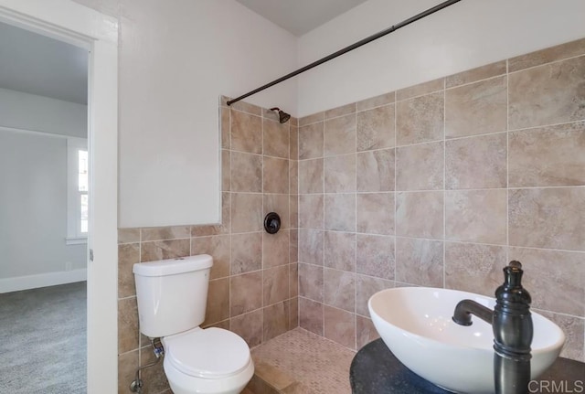 bathroom featuring tiled shower, toilet, and tile walls