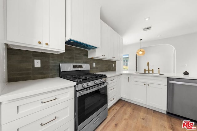 kitchen with white cabinets, decorative light fixtures, stainless steel appliances, sink, and custom range hood