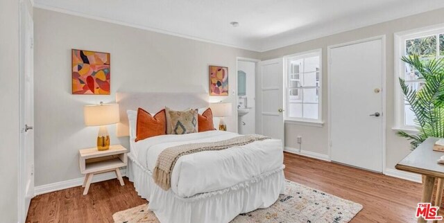 bedroom featuring connected bathroom, ornamental molding, and light hardwood / wood-style floors