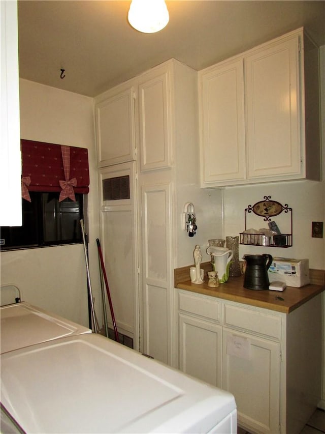 kitchen with butcher block counters and white cabinetry