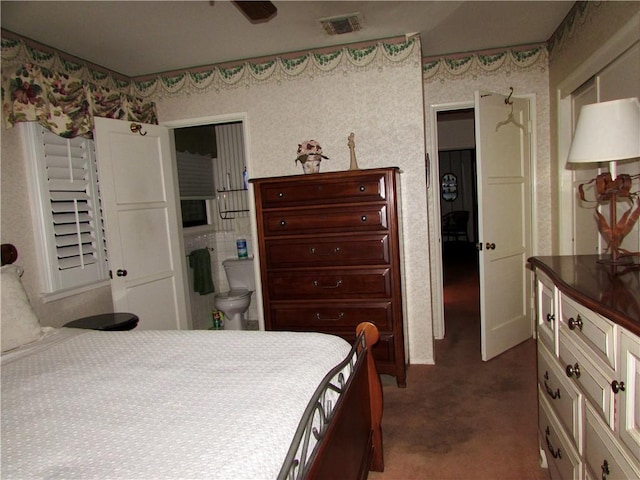 bedroom with ensuite bathroom and carpet floors