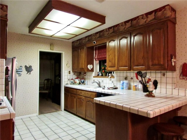 kitchen with tile counters, decorative backsplash, and kitchen peninsula