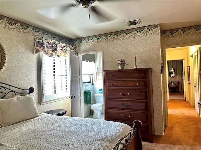 carpeted bedroom with ceiling fan and ensuite bath