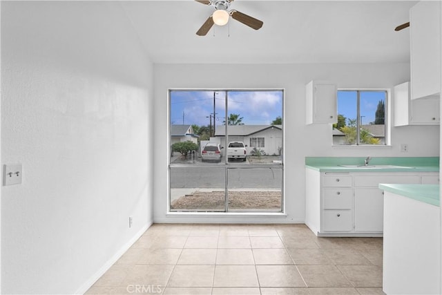 unfurnished dining area featuring ceiling fan, light tile patterned floors, and sink