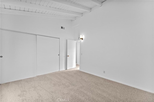 carpeted spare room featuring high vaulted ceiling and beamed ceiling