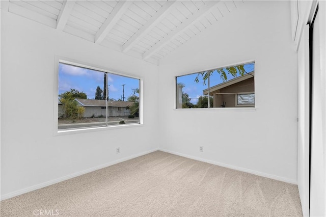 carpeted empty room featuring wood ceiling and lofted ceiling with beams